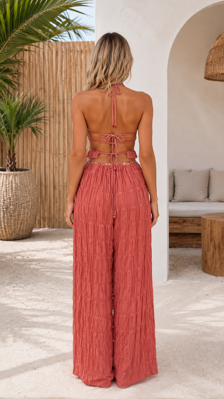 Back view of dusty rose textured halter crop top and wide-leg pants set with open tie-back detail