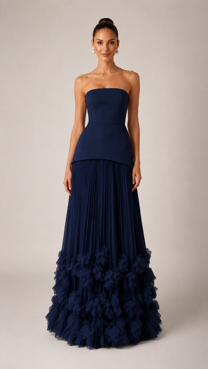 Front view of navy strapless pleated maxi gown with sculpted bodice and ruffle hem