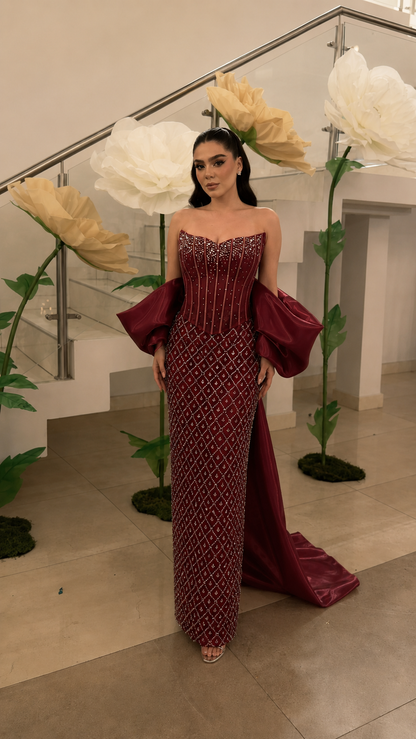 Burgundy beaded strapless evening gown with dramatic off-arm draped sleeves front view