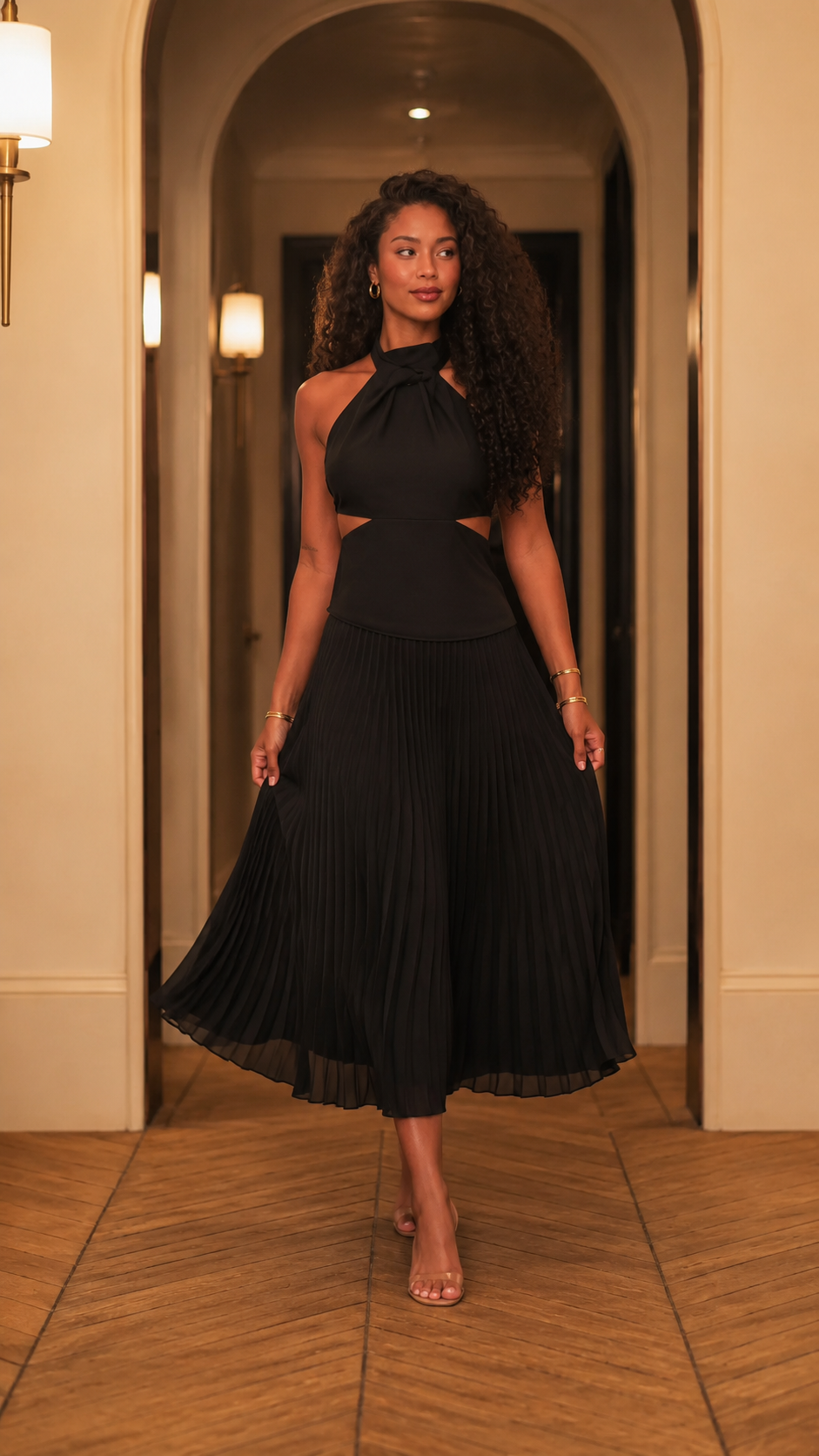 Front view of black halter pleated midi dress with side cutout waist detail