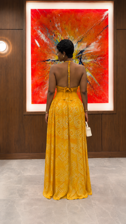 Back view of mustard halter neck maxi dress with tie-back detail and open upper back