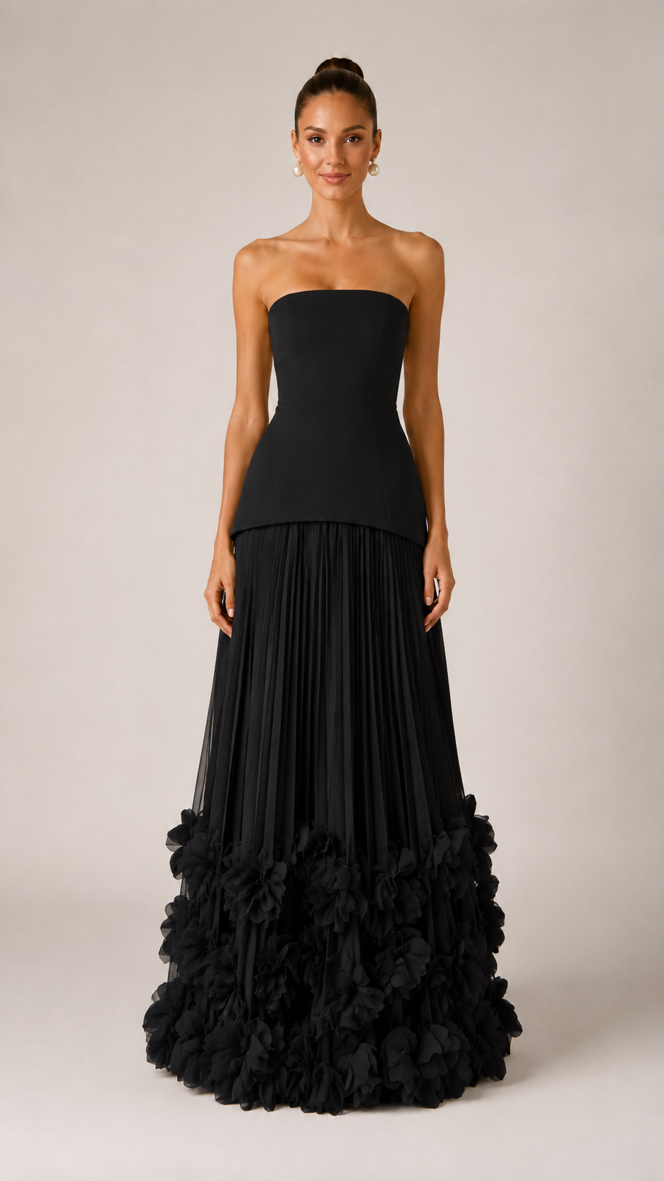 Front view of black strapless maxi gown with pleated skirt and statement ruffle hem