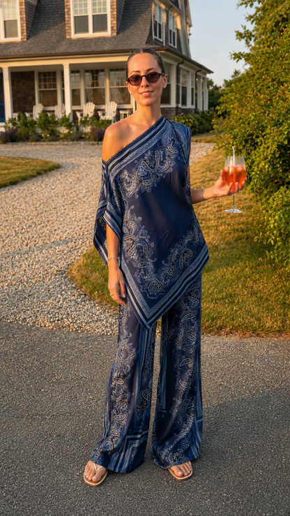 Model wearing navy printed one-shoulder draped top with matching wide leg pants