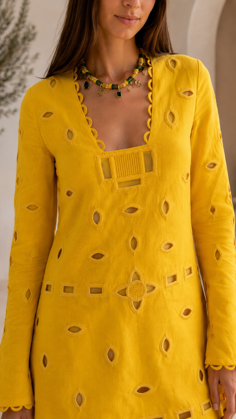 Close-up of yellow mini dress showing square neckline, front trim, and cutout embroidery
