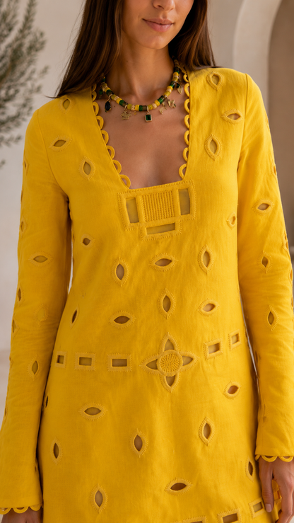 Close-up of yellow mini dress showing square neckline, front trim, and cutout embroidery